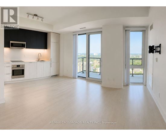 A spacious, empty room with a view of the city through large windows.