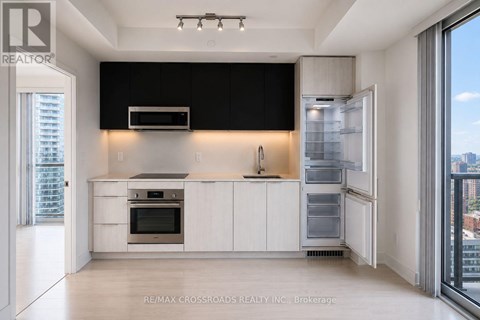 A modern kitchen with white cabinets and a black backsplash.