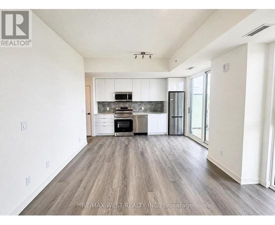 A spacious kitchen with white cabinets and a wooden floor.