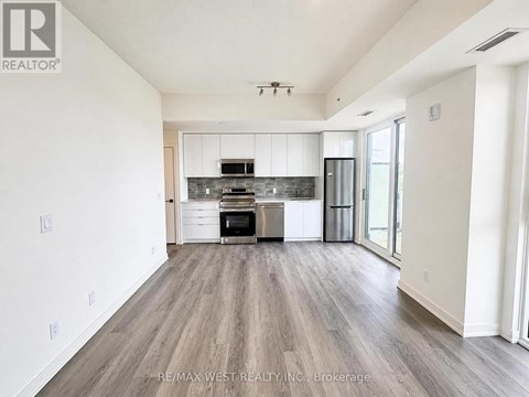 A spacious kitchen with white cabinets and a wooden floor.