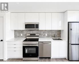 A modern kitchen with white cabinets and stainless steel appliances.