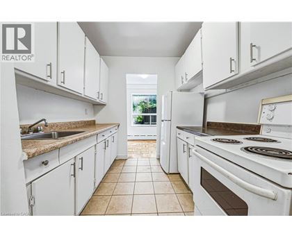 A white kitchen with a tile floor and white appliances.