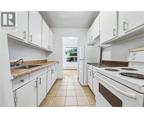 A white kitchen with a tile floor and white appliances.