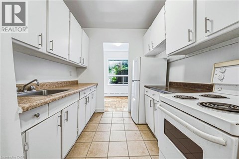 A white kitchen with a tile floor and white appliances.