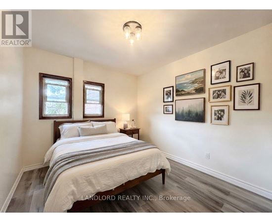 A bedroom with a bed, nightstand, and pictures on the wall.