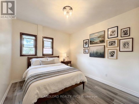 A bedroom with a bed, nightstand, and pictures on the wall.