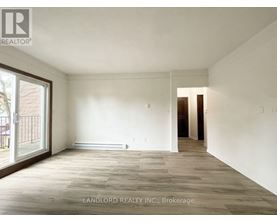 A spacious room with wooden flooring and white walls, part of a property managed by Landlord Realty Inc.