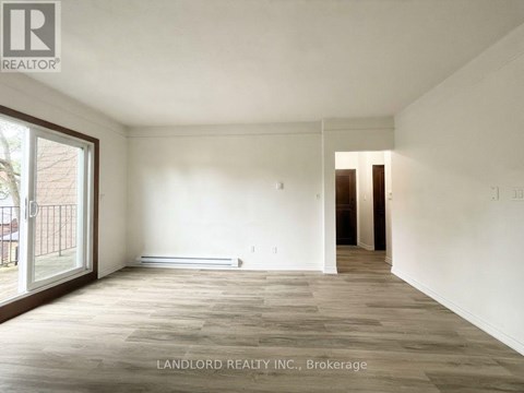 A spacious room with wooden flooring and white walls, part of a property managed by Landlord Realty Inc.