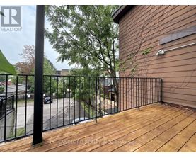 A wooden deck with a metal railing and a building in the background.