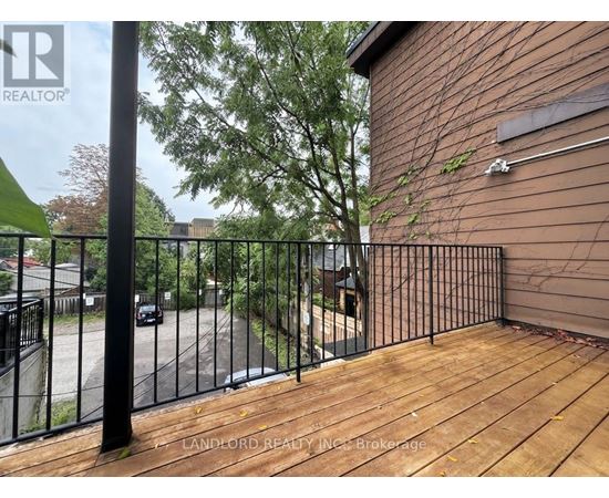 A wooden deck with a metal railing and a building in the background.