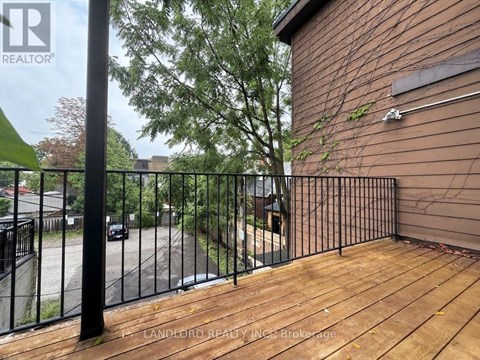 A wooden deck with a metal railing and a building in the background.