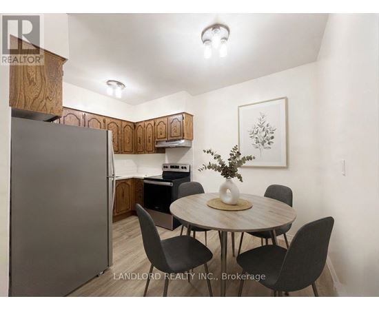 A kitchen with a table and chairs in the foreground and a refrigerator in the background.