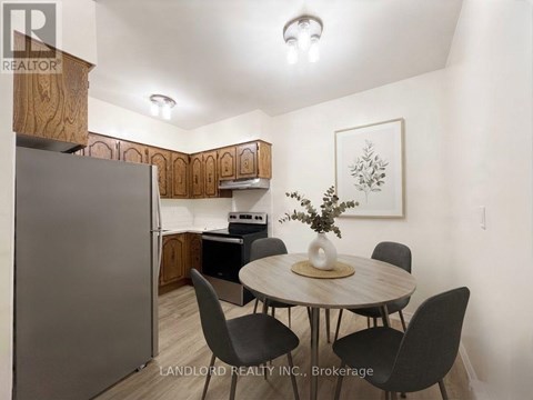 A kitchen with a table and chairs in the foreground and a refrigerator in the background.