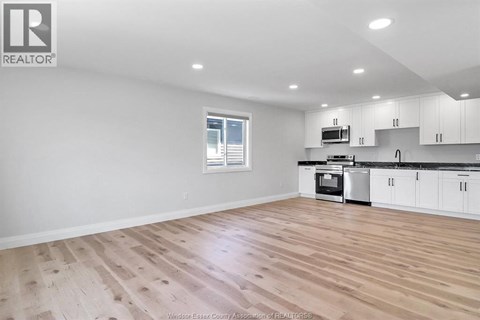 A spacious kitchen with white cabinets and a wooden floor.