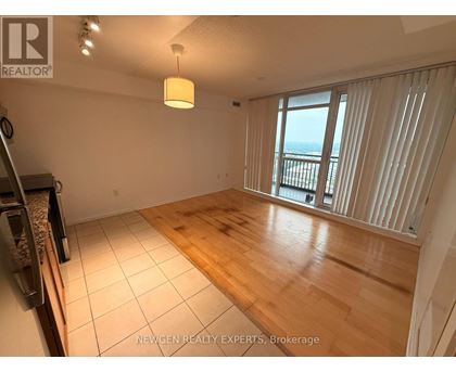 A spacious room with wooden flooring and a large window overlooking the ocean.