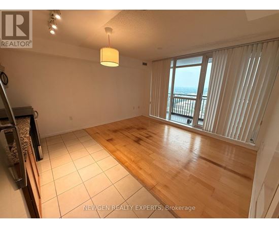 A spacious room with wooden flooring and a large window overlooking the ocean.