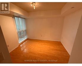 A room with wooden flooring and a window with blinds.