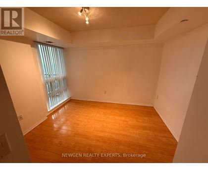 A room with wooden flooring and a window with blinds.