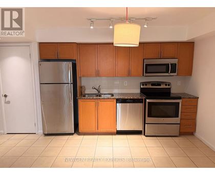 A kitchen with wooden cabinets and a stainless steel refrigerator.