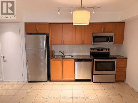 A kitchen with wooden cabinets and a stainless steel refrigerator.
