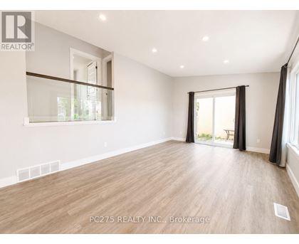 A spacious room with wooden flooring and a sliding glass door leading to a balcony.
