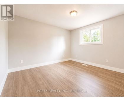 A room with wooden flooring and a window showing greenery outside.