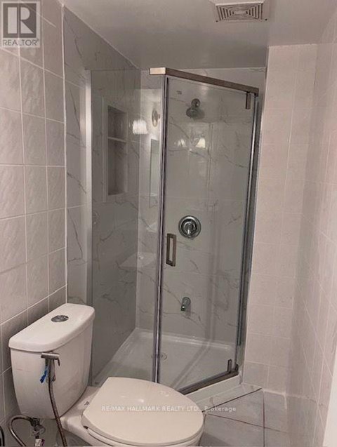 A white toilet with a towel rack and a glass shower stall with a door.