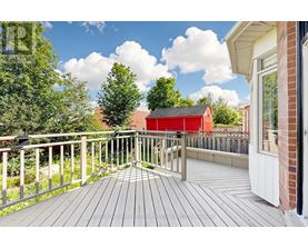 A wooden deck with a railing and a red building in the background.