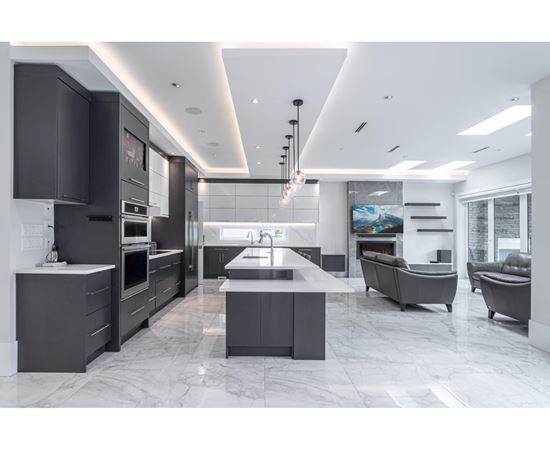 A modern kitchen with a marble floor and grey cabinets.