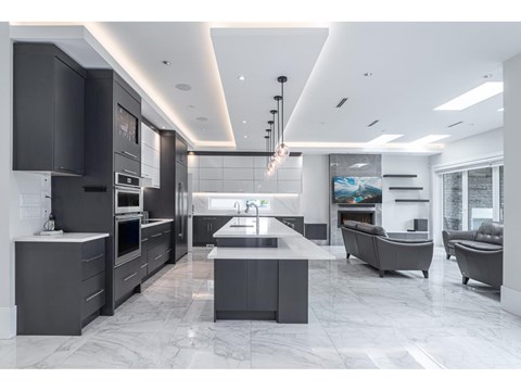 A modern kitchen with a marble floor and grey cabinets.
