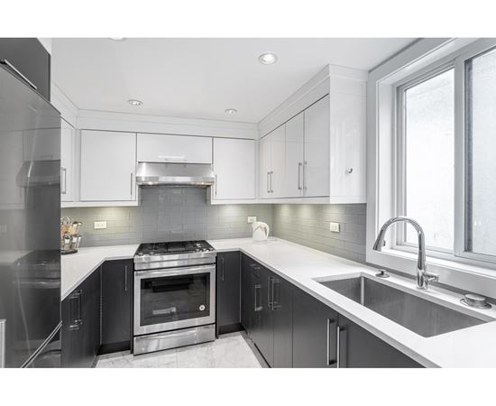 A modern kitchen with a stove top oven and a sink.