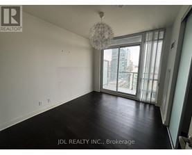 A spacious room with a chandelier and large windows overlooking a cityscape.
