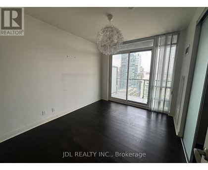 A spacious room with a chandelier and large windows overlooking a cityscape.