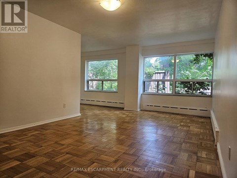 A room with wooden flooring and large windows.