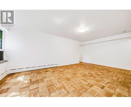 A room with wooden flooring and white walls.