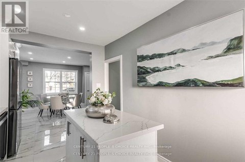 A modern kitchen with a marble island and a painting on the wall.