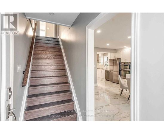 A staircase with wooden steps leads to a brightly lit room.