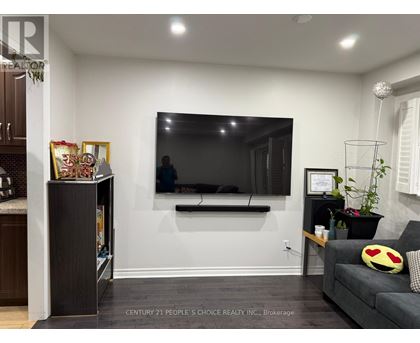A living room with a grey couch and a flat screen TV mounted on the wall.