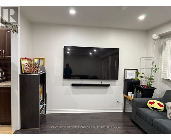 A living room with a grey couch and a flat screen TV mounted on the wall.