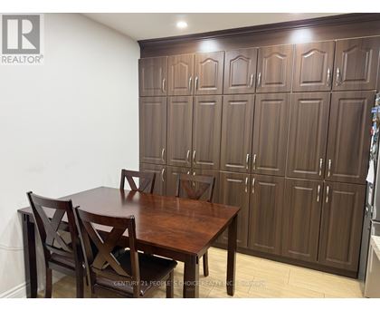 A brown wooden dining table with four chairs in front of a wall with a logo that says REALTOR.