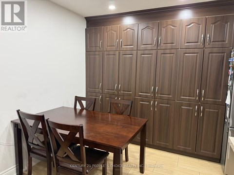 A brown wooden dining table with four chairs in front of a wall with a logo that says REALTOR.