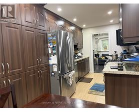 A kitchen with wooden cabinets and a stainless steel refrigerator.