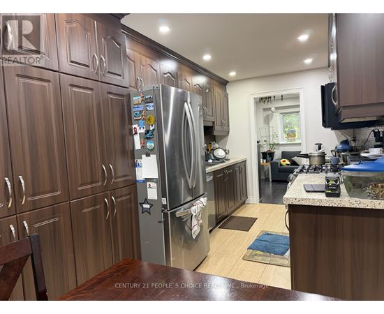 A kitchen with wooden cabinets and a stainless steel refrigerator.