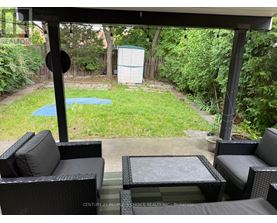 A patio with black wicker furniture and a pool in the backyard.
