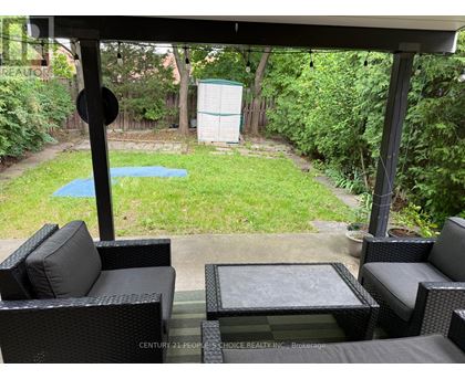 A patio with black wicker furniture and a pool in the backyard.