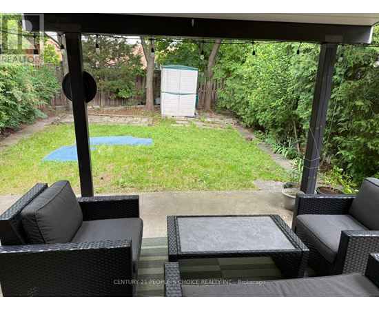 A patio with black wicker furniture and a pool in the backyard.