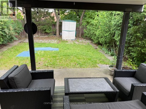 A patio with black wicker furniture and a pool in the backyard.