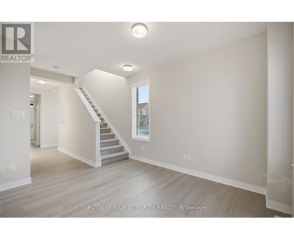 A spacious room with a staircase leading to the second floor.