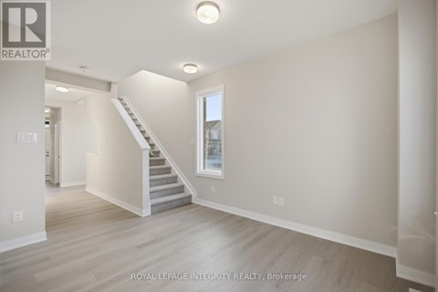 A spacious room with a staircase leading to the second floor.
