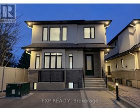 A modern house with a dark front porch and a green dumpster in front.